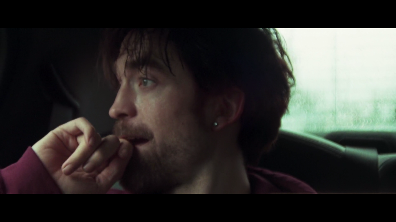 Robert Pattinson staring out car window in Good Time